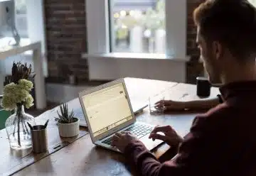 man operating laptop on top of table